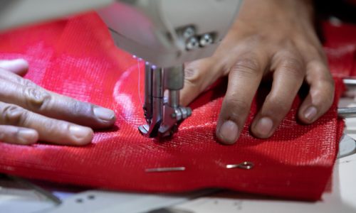 Man Sewing a Red Shade Sail Man Sewing a Red Shade Sail